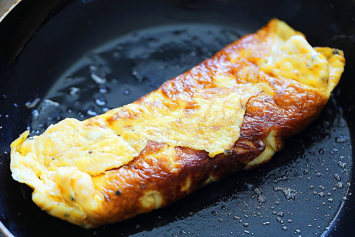 Tube-shaped omelet in a skillet.
