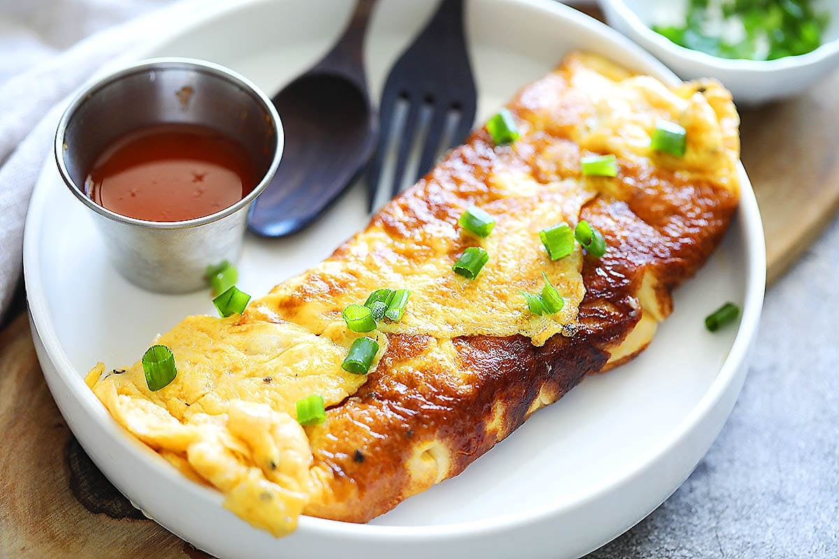 Pan-fried crab omelette just like in Bangkok, topped with scallions and served with Thai sriracha chili sauce.