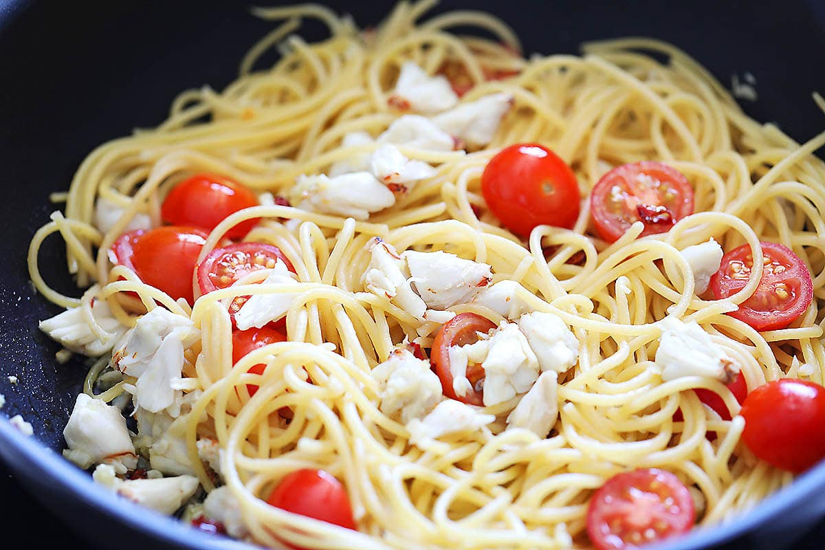 Spaghetti, cherry tomatoes and crab lump meat in a pan.