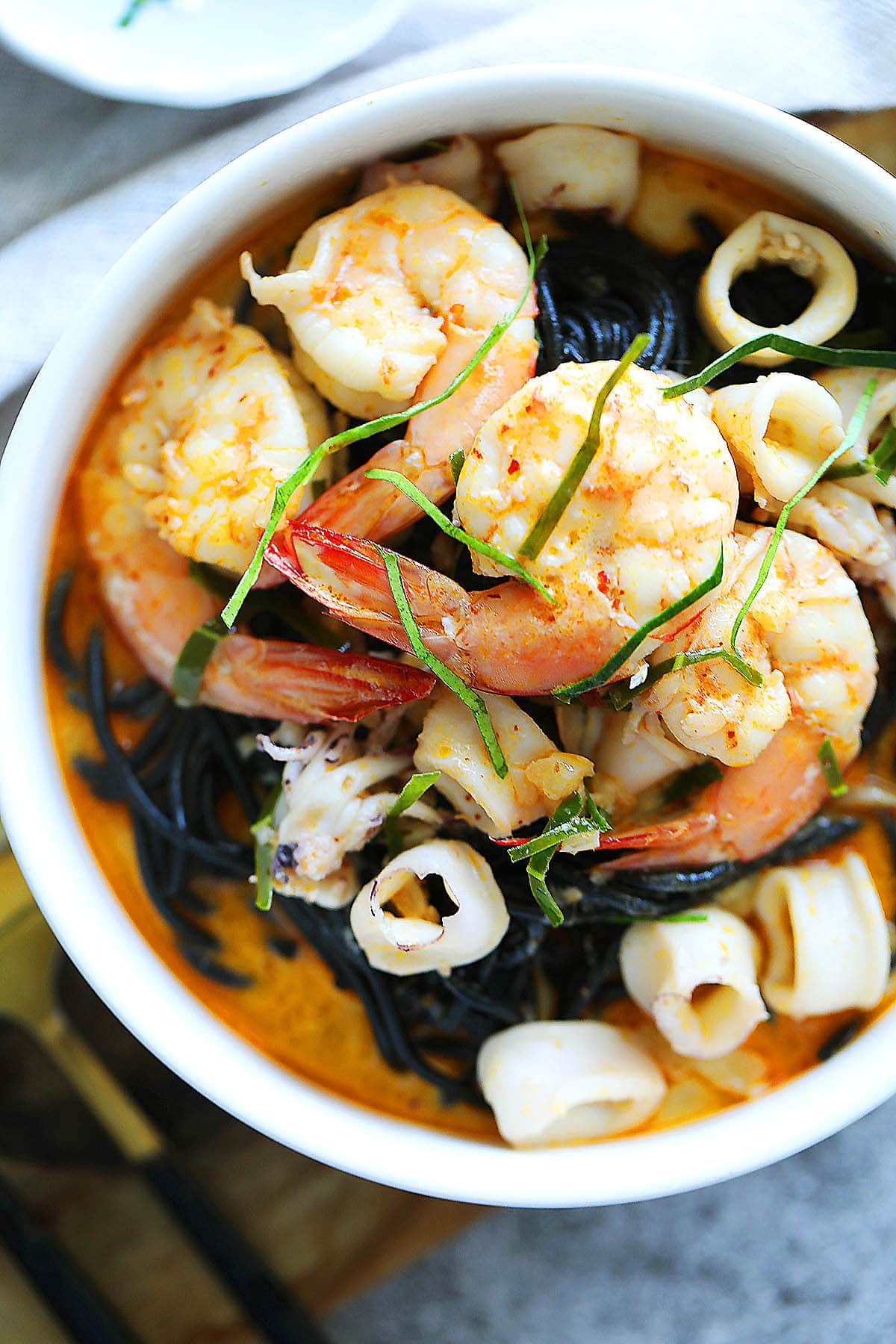 Seafood squid ink pasta with creamy tom yum sauce served in a bowl.