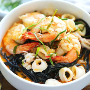 Squid ink pasta with seafood coated in a creamy and saucy tom yum sauce.