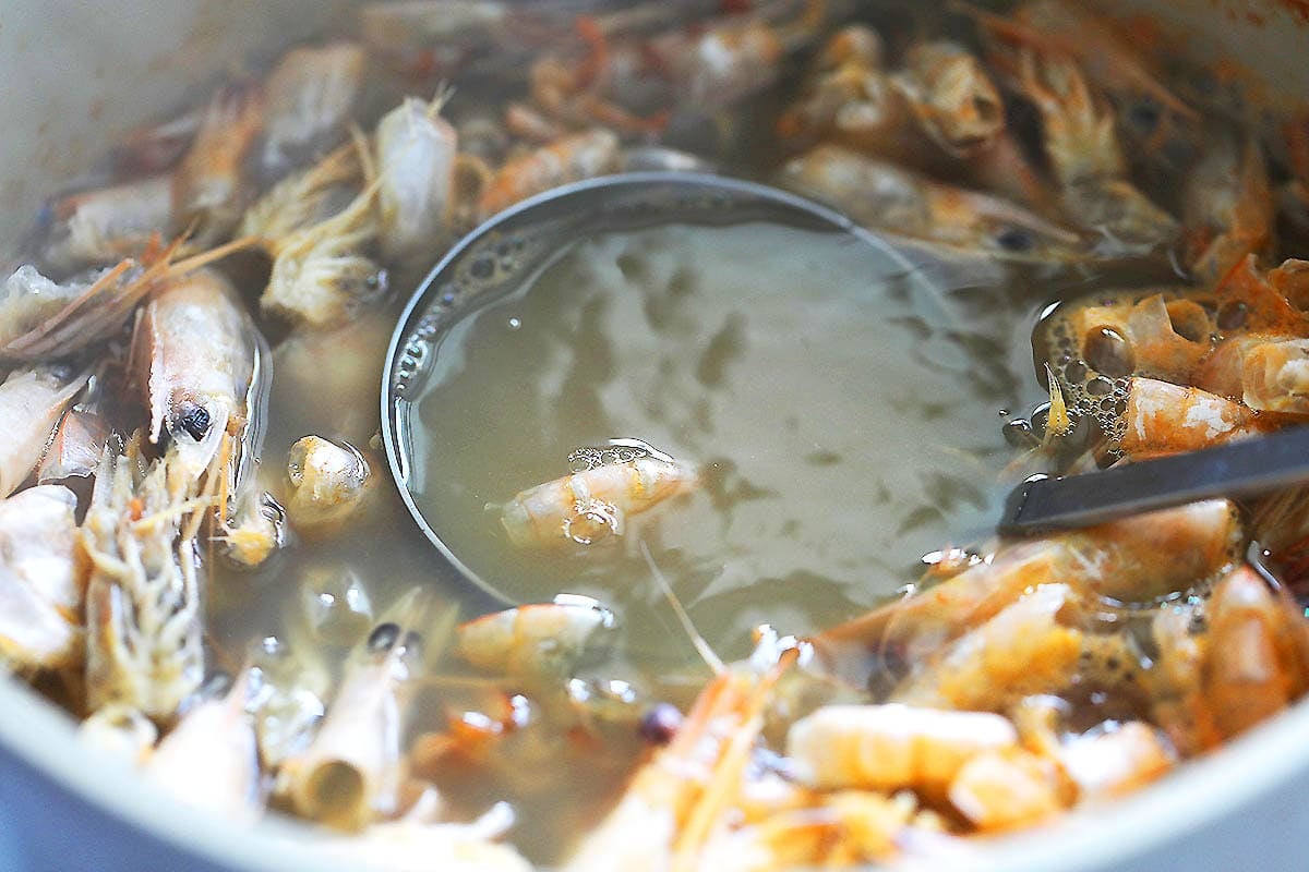 Shrimp shells and heads in a pot of water.