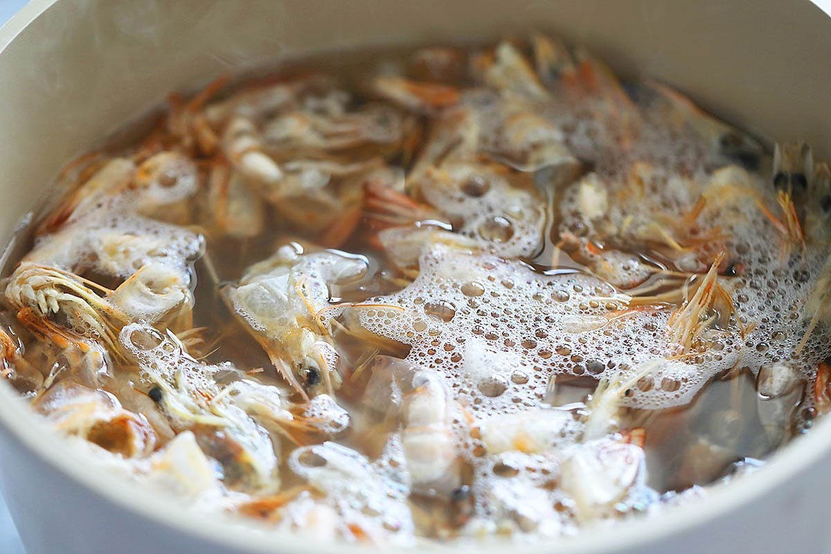 Shrimp shells and heads in a pot of boiling water.