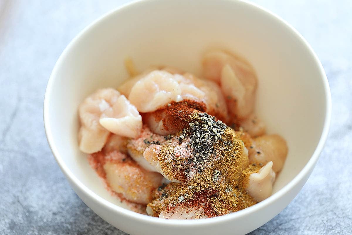 Chicken breast, ground cumin, smoked paprika, salt, and black pepper in a bowl.