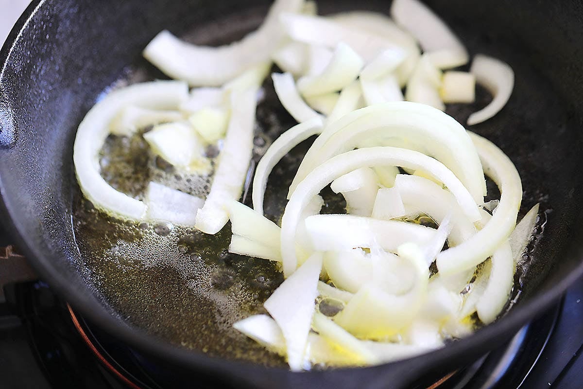 Oil, melted butter, and onions in a cast iron skillet.