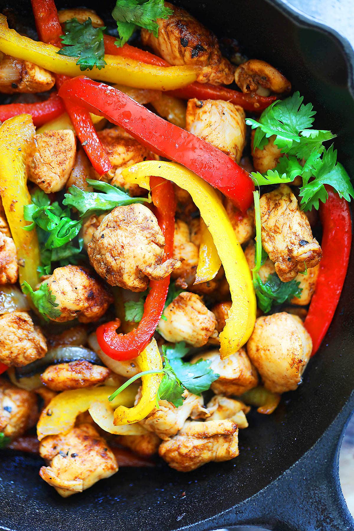 Sizzling chicken fajita garnished with cilantro in a cast iron skillet.