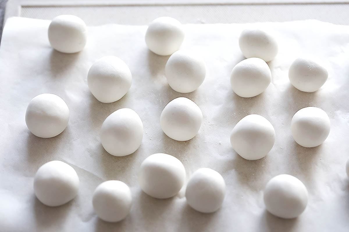 Uncooked rice dumpling balls on a parchment paper.