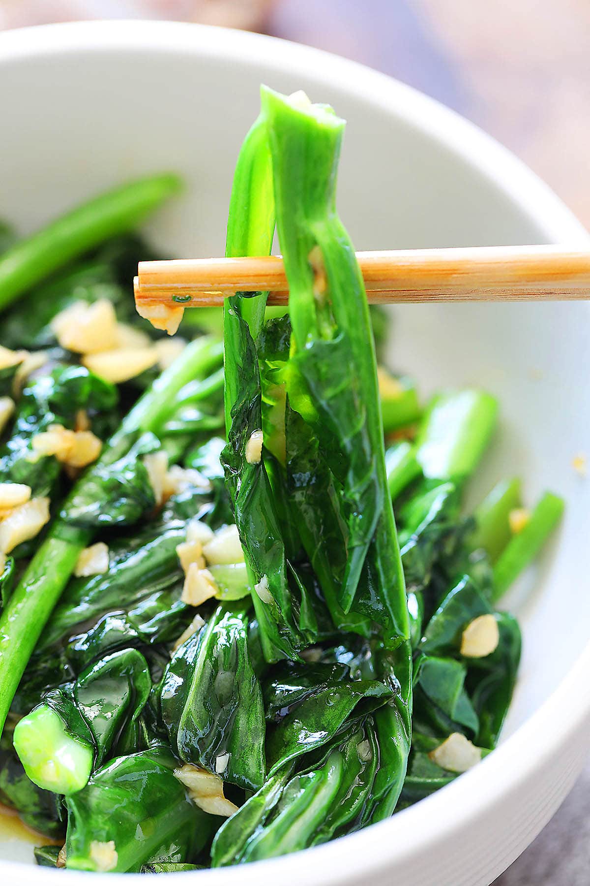 Chinese broccoli with oyster sauce picked up with a pair of chopsticks.