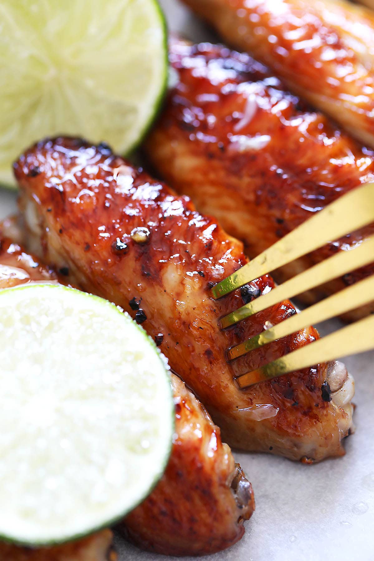 Honey lime chicken wings pierced with a fork.