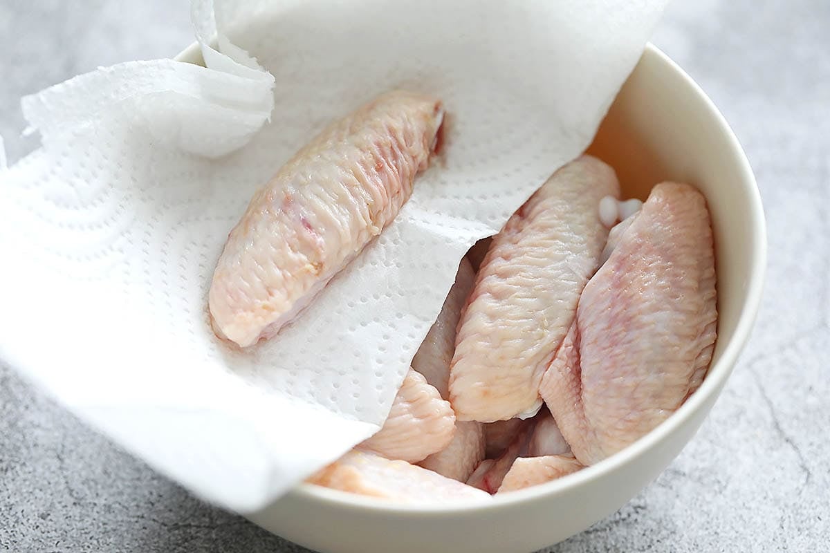 Paper towel on a bowl of raw chicken wingettes.