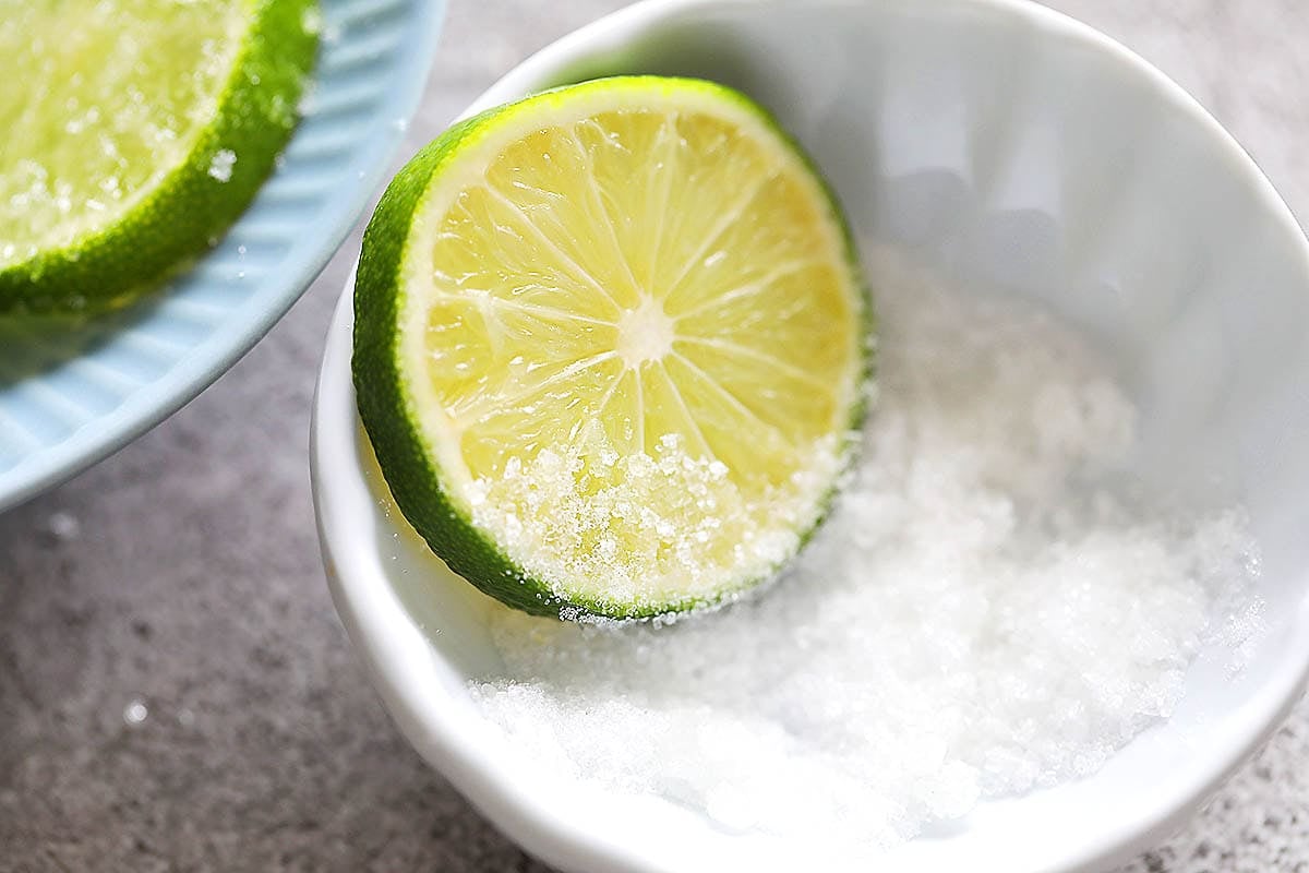 A lime slice in a small bowl of white sugar.