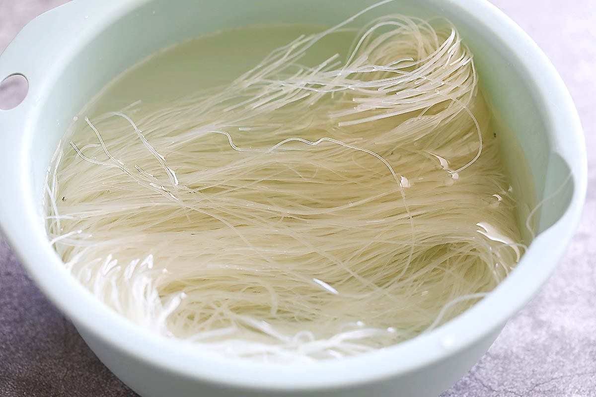 Dried rice noodles in a bowl of water.