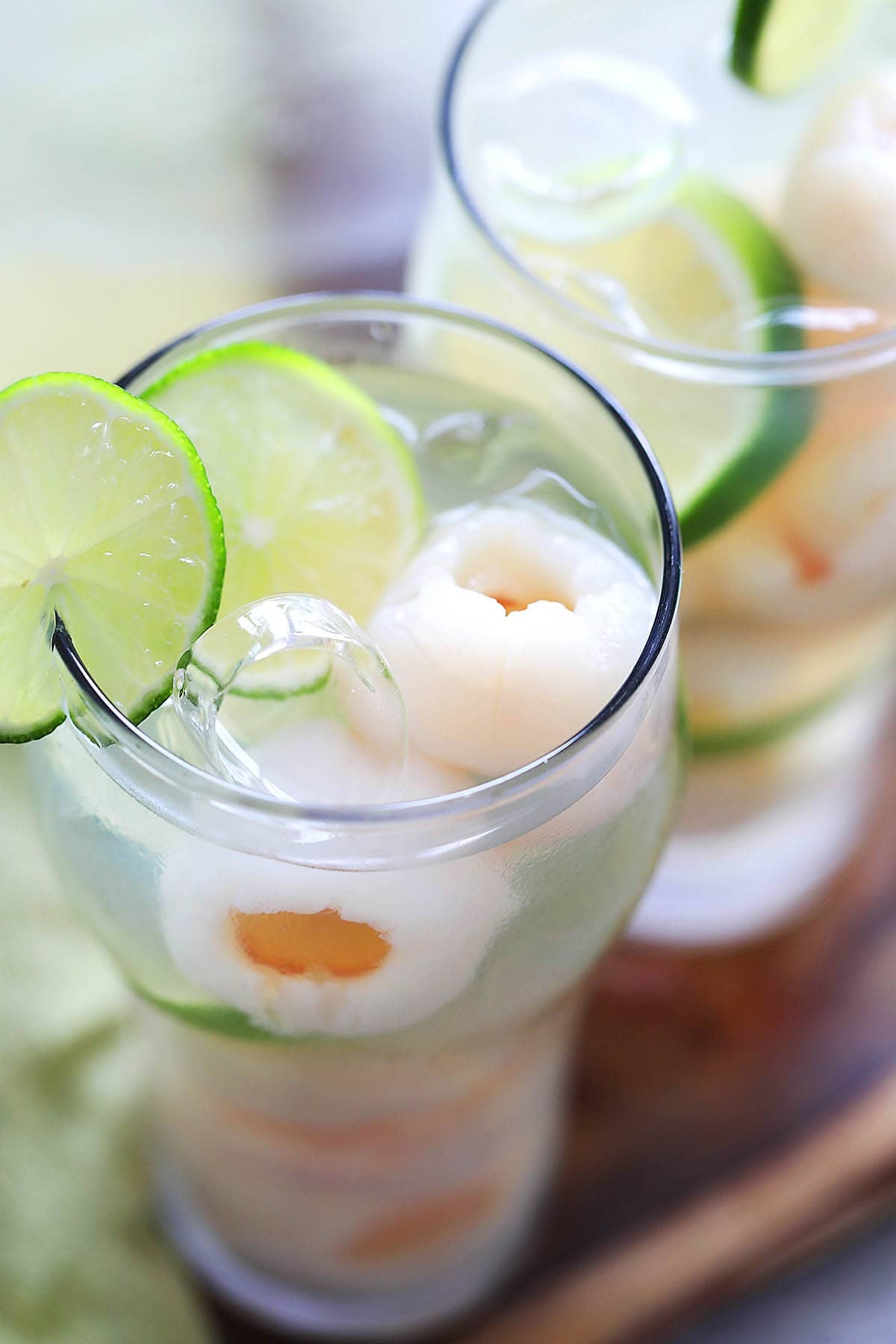Iced lychee drink in serving glasses and garnished with a slice of lime.