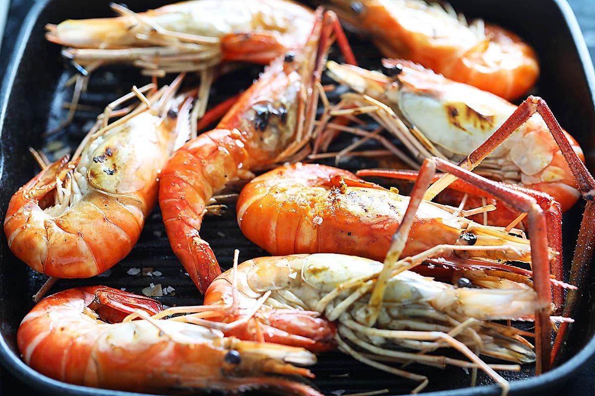 Reddish shrimp sprinkled with sea salt flakes in a grill pan.