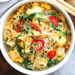 Egg fried noodles garnished with white sesame seeds and red chili.
