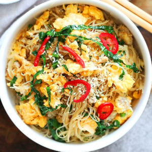 Egg fried noodles garnished with white sesame seeds and red chili.