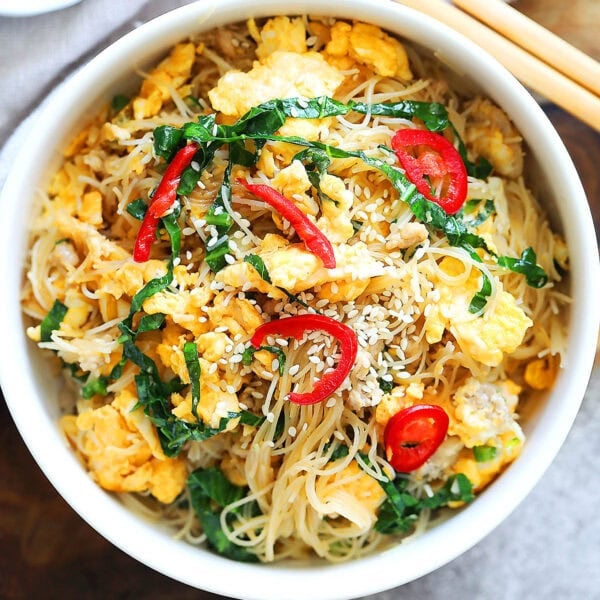 Egg fried noodles garnished with white sesame seeds and red chili.