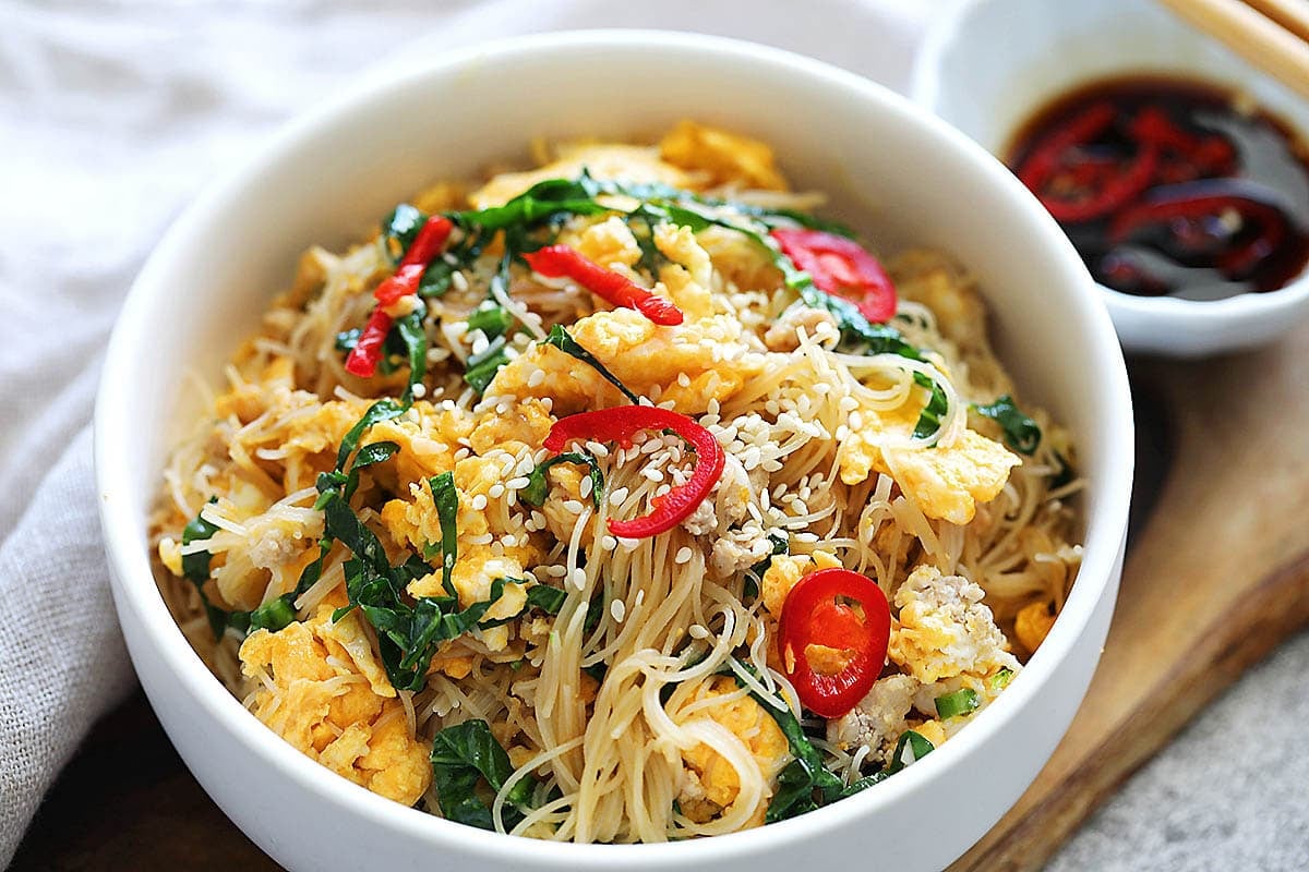 Chinese egg fried noodles recipe garnished with sesame seeds and sliced red chili.