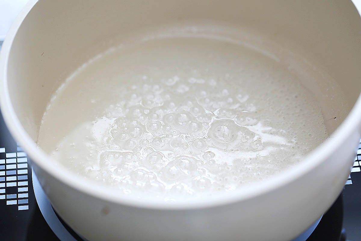 Sugar mixture gently boiling in a saucepan.