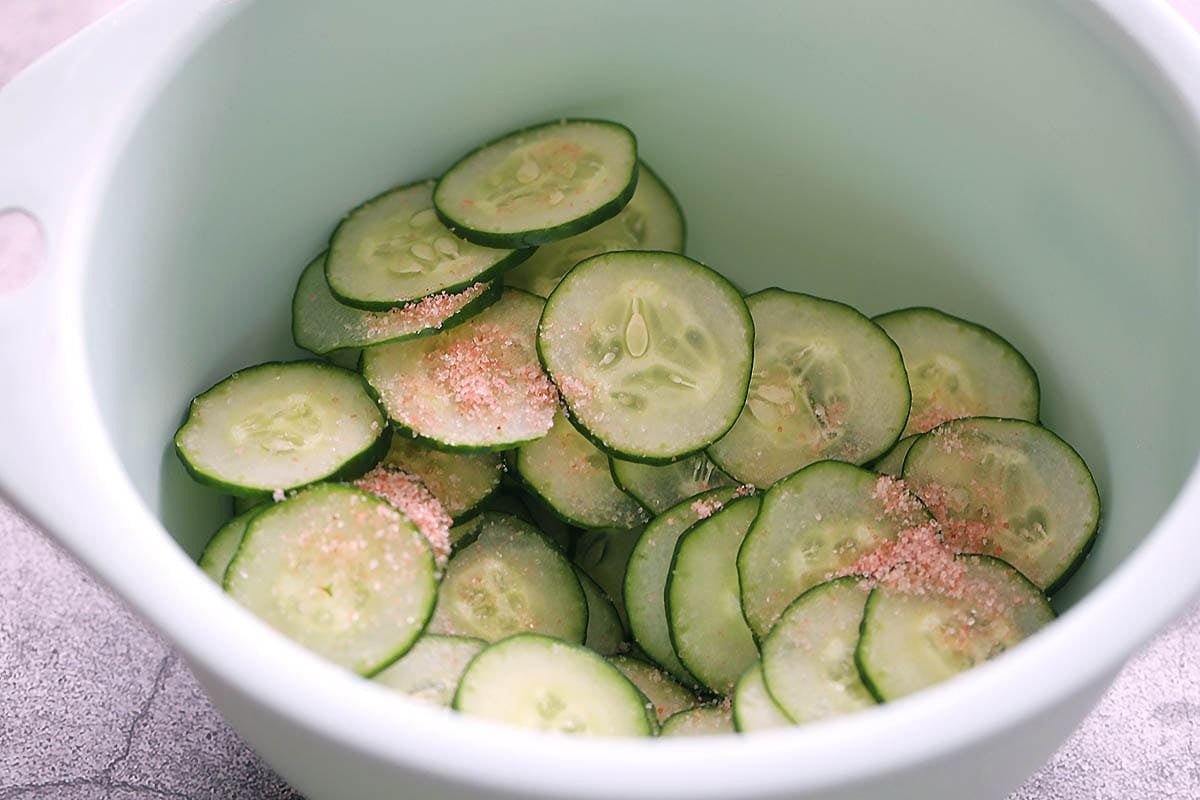 Cucumber slices and salt in a bowl.