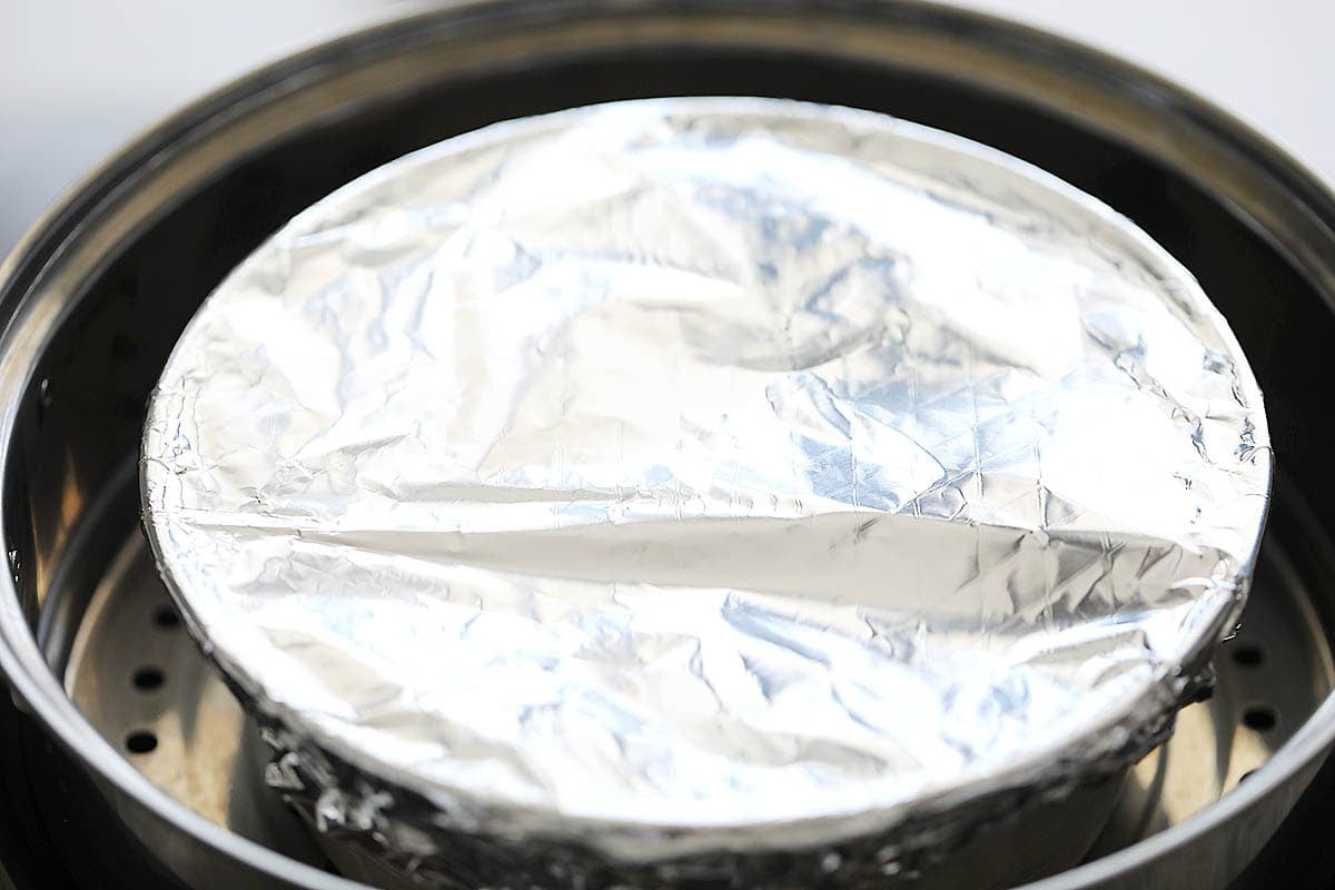 Cake pan covered with aluminum foil in a steamer.
