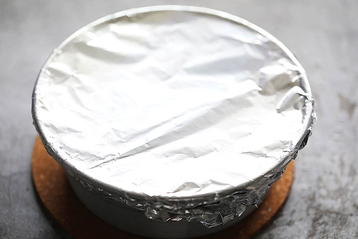 Cake pan covered with aluminum foil on a counter.
