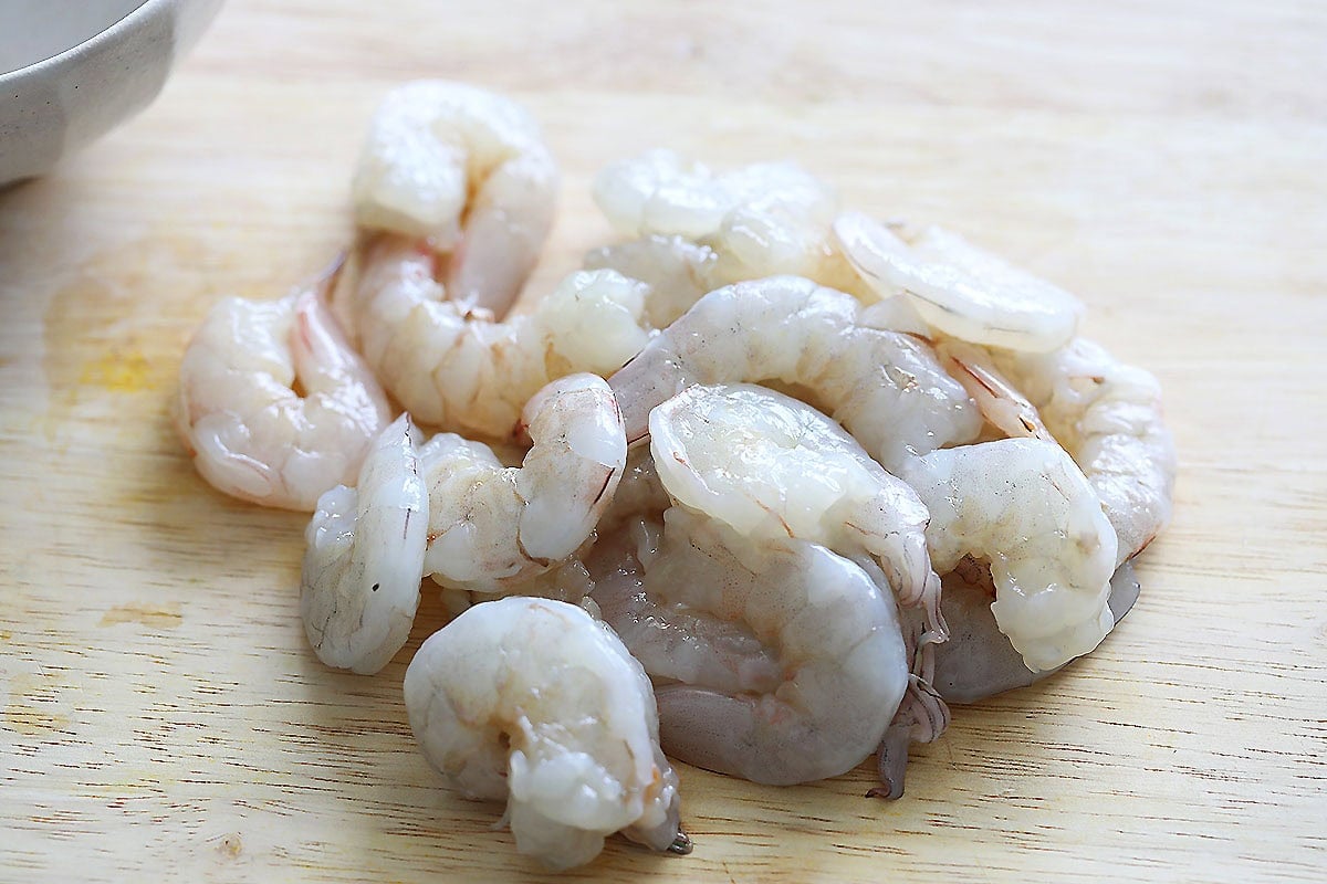 Peeled and deveined shrimp on a chopping board.
