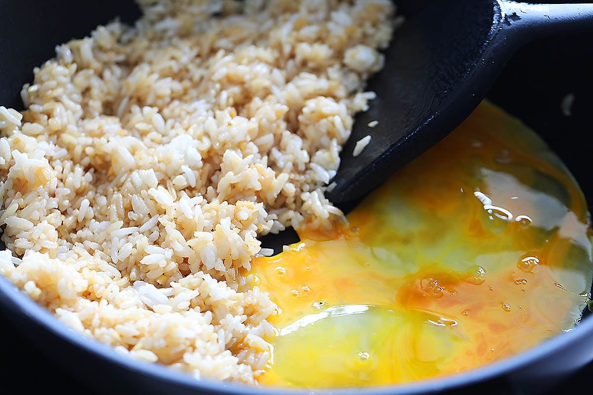 Rice and beaten eggs in a pan.