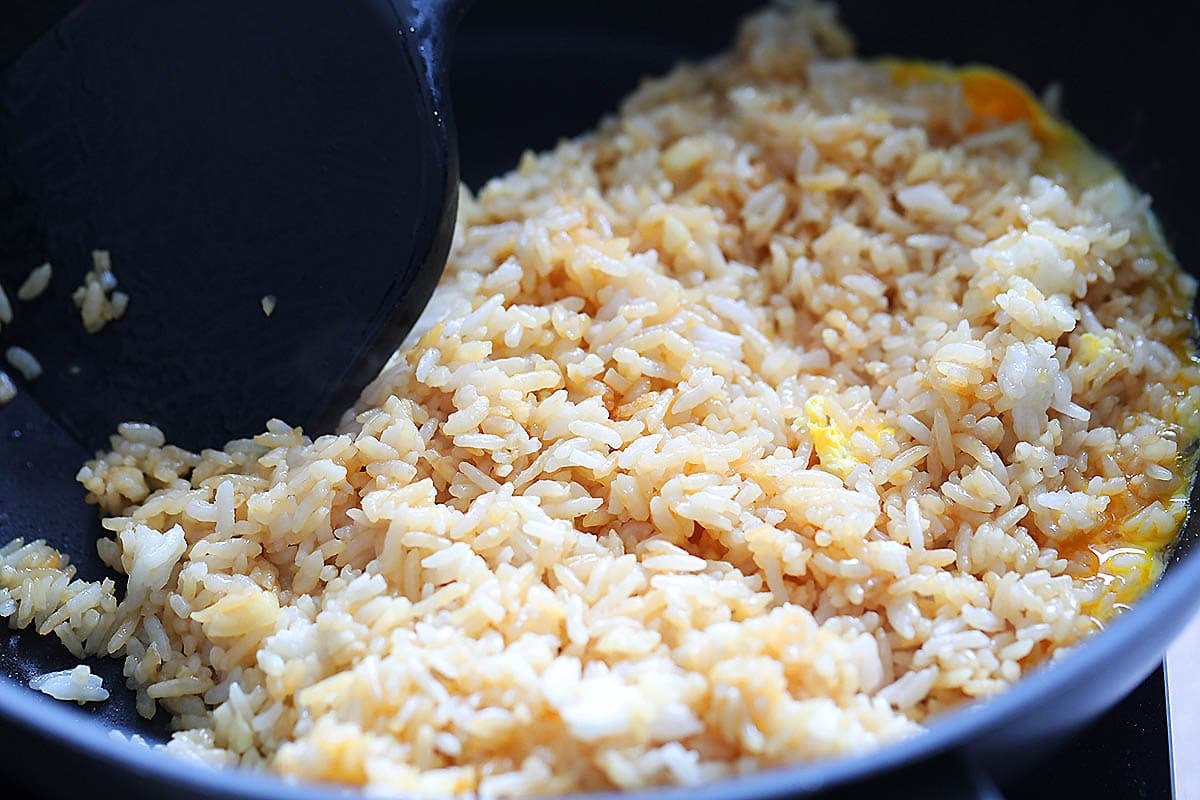 Rice folded over the eggs in a pan.
