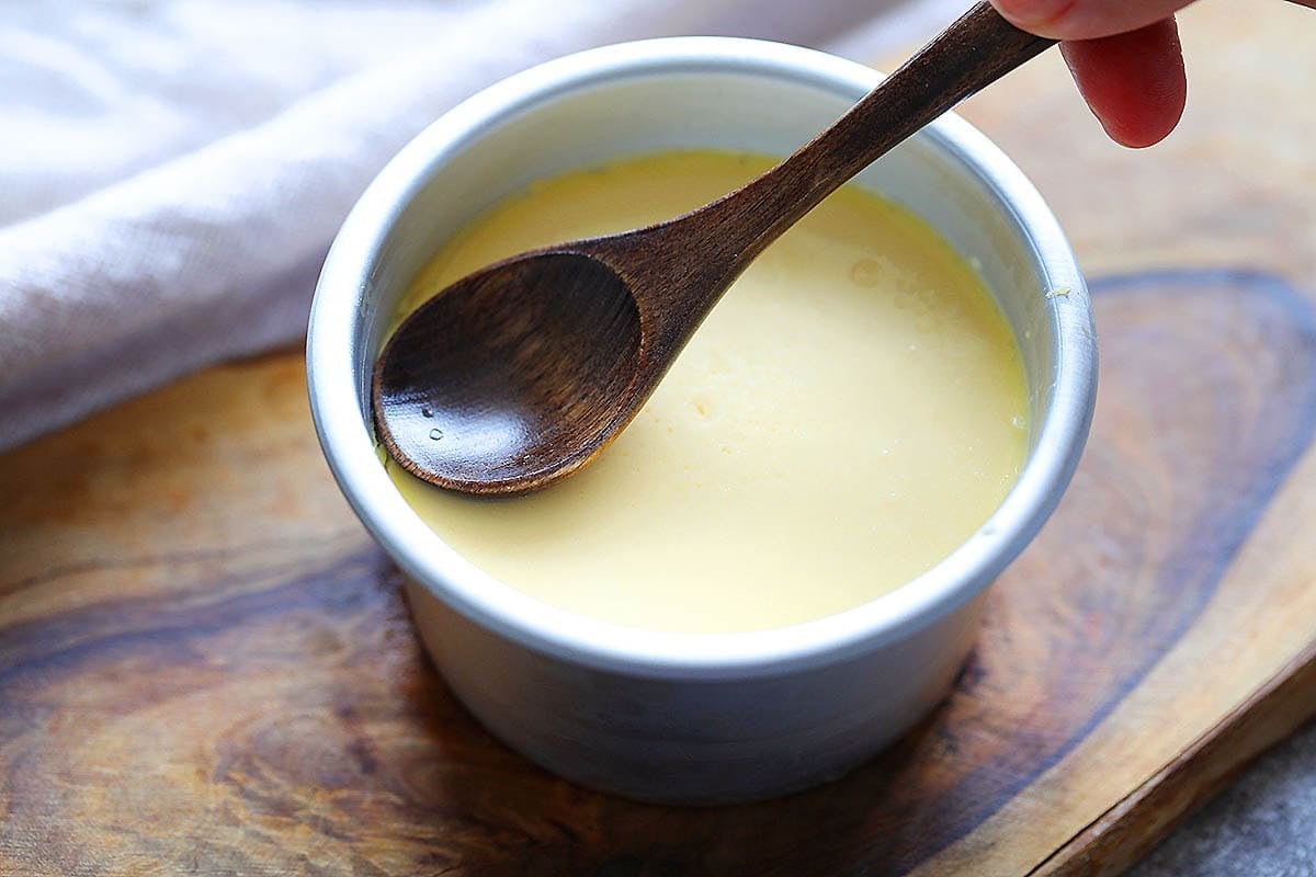 Spoon pressing along the edge of the creme caramel.