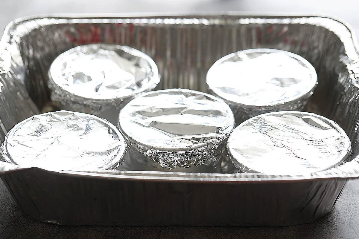 Covered tin molds in a baking tray.