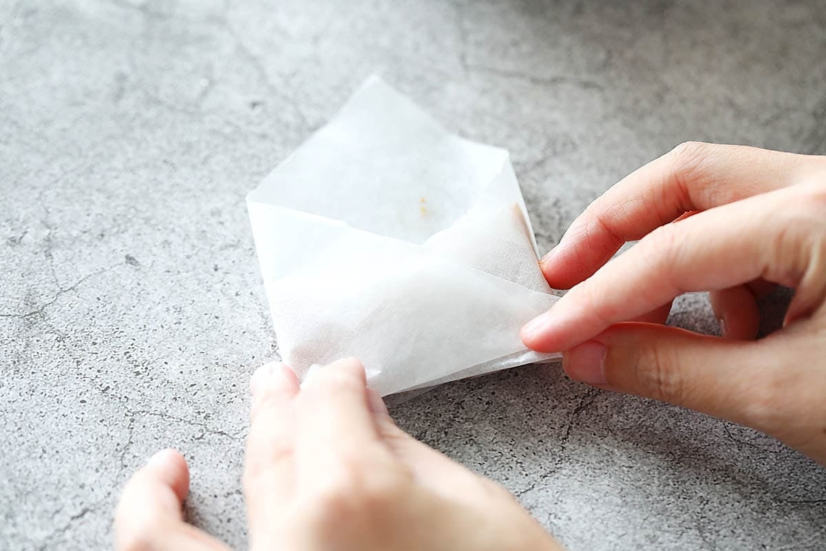 Left corner of the parchment paper being folded to the center.