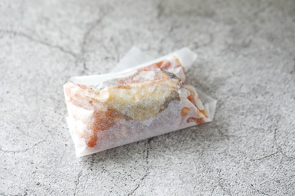 Parcel rolled upwards towards the top corner of the parchment paper.