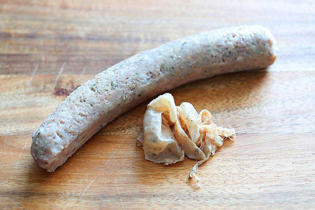 Sausage and it's casing on a chopping board.