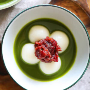 Matcha zenzai served in a small bowl with red bean paste, shiratama dango and matcha tea.
