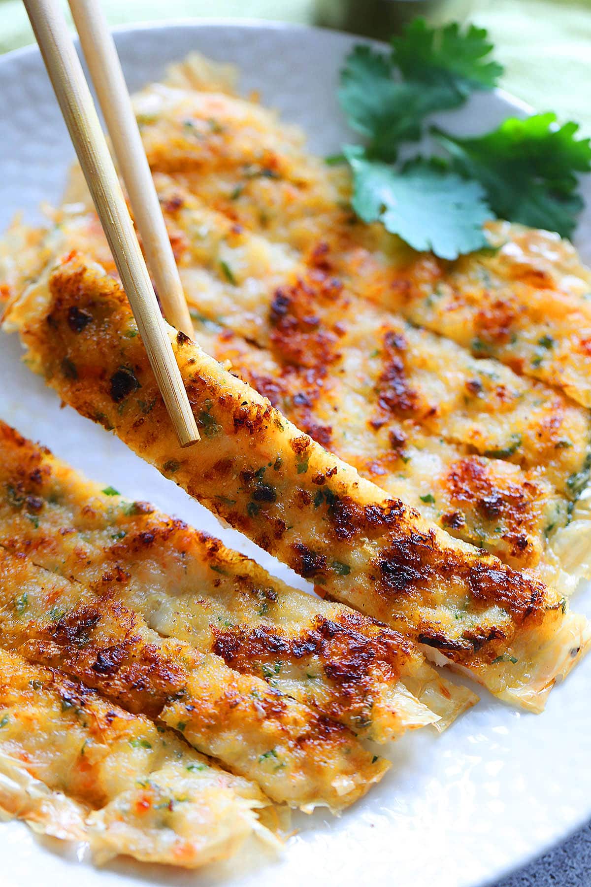 A slice of dim sum prawn cake picked with a pair of chopsticks.