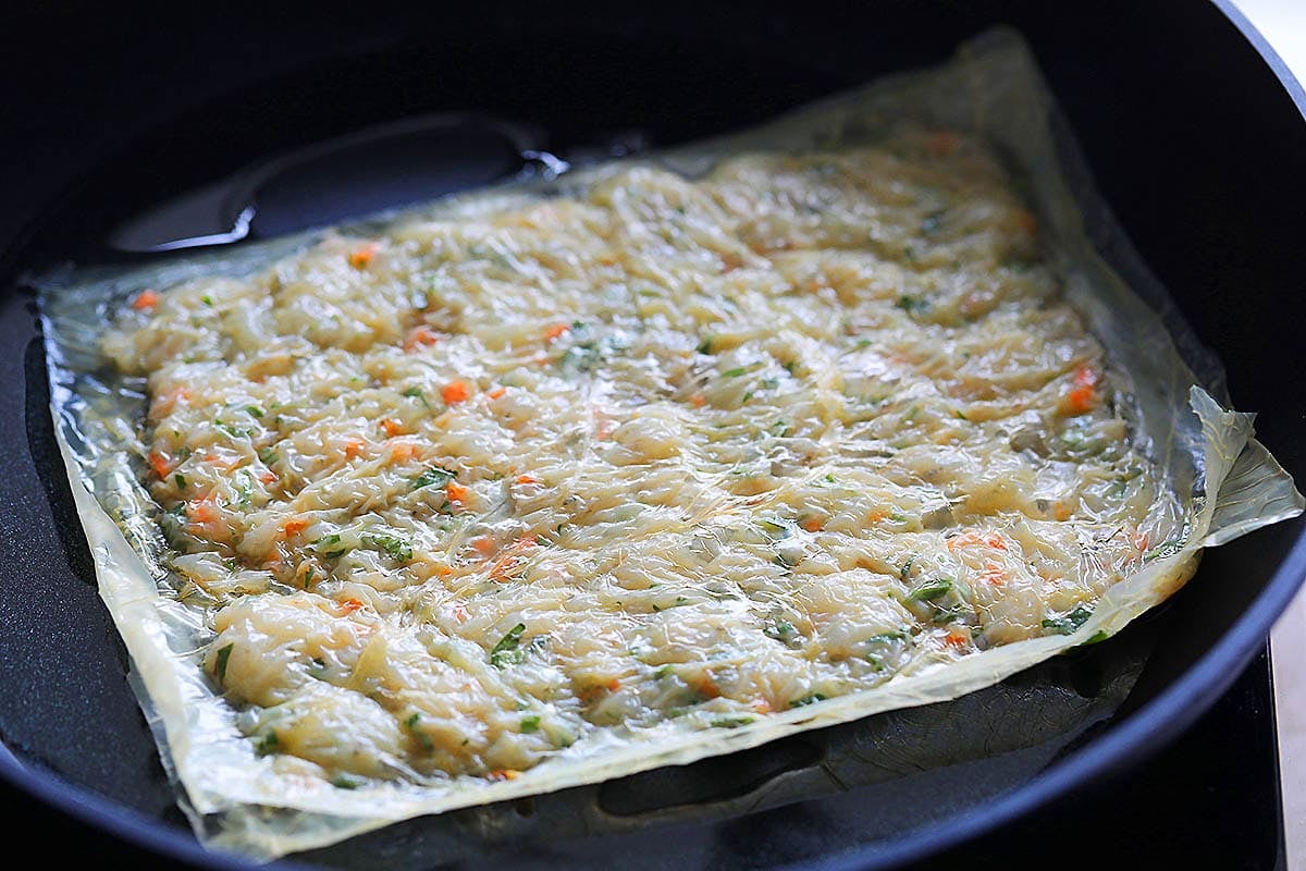 Prawn cake shallow fried in a pan.