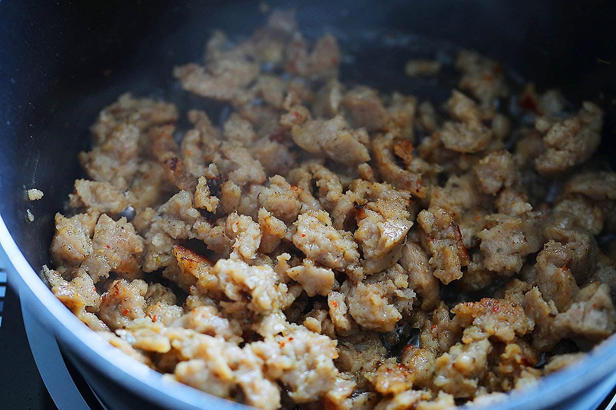 Golden brown pork sausage in a saucepan.