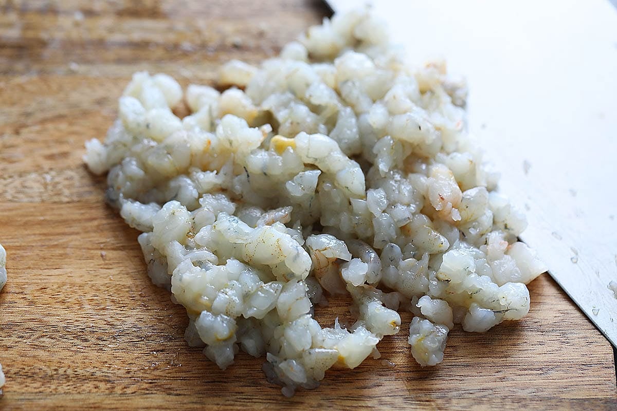 Small pieces of shrimp on a chopping board.