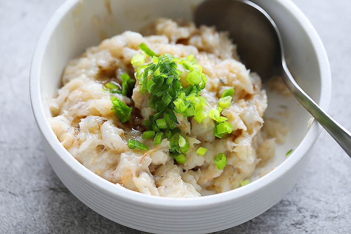 Shrimp mousse, fish sauce, and chopped scallions in a bowl.
