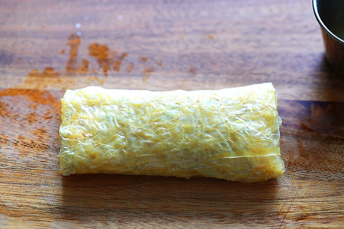 Raw bean curd shrimp roll on a chopping board.