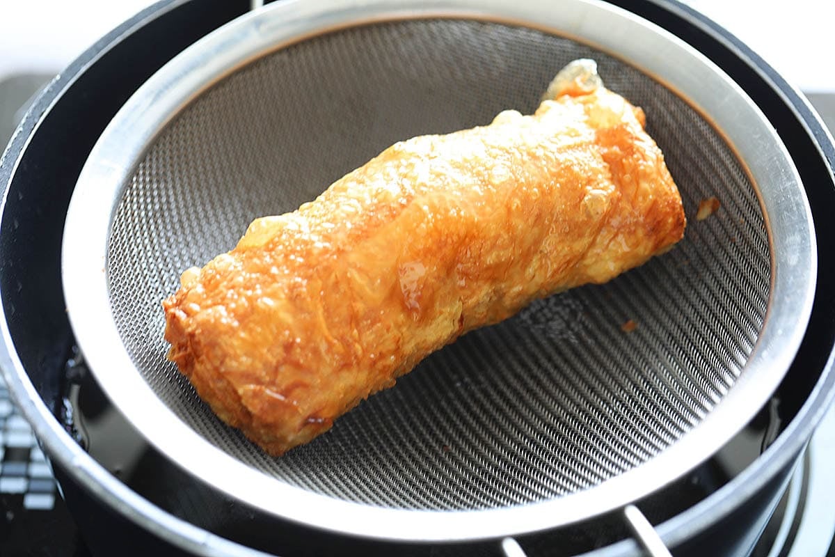 Crispy golden bean curd shrimp roll on a strainer.