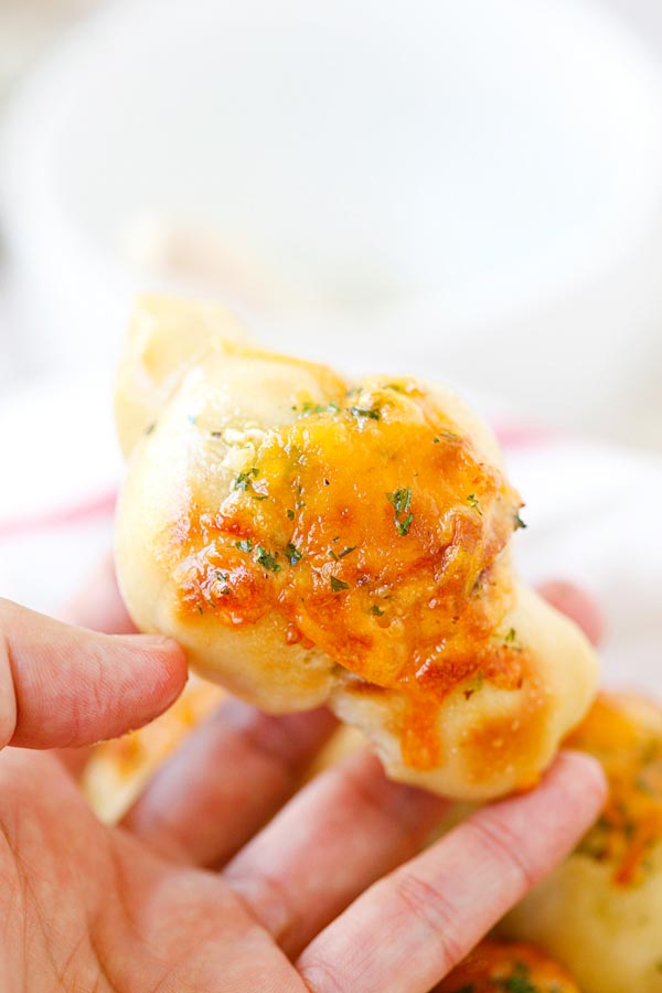 Easy homemade mini crescent rolls with cheddar cheese and garlic butter held in hand.