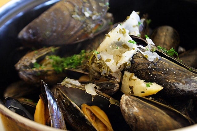Raw mussels with garlic white wine sauce in a pot.